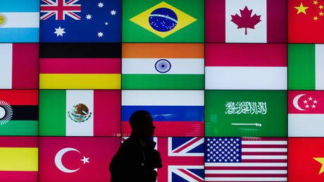 FILE PHOTO: A man walks past a screen displaying flags of G20 countries.