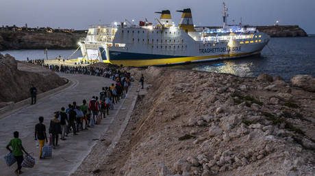 FILE PHOTO: Migrants embarking on the Lampedusa ferry headed to the Italian mainland