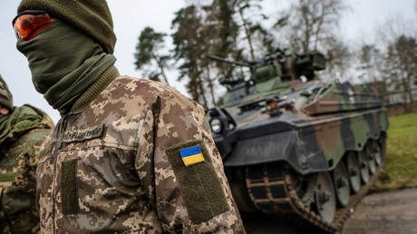 An Ukrainian soldier translator stands in front of a Marder infantry fighting vehicle.